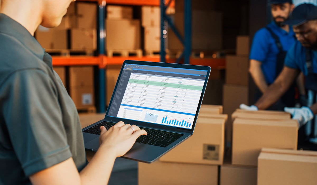 Gestor logístico calcula TCO en tablet junto a cajas y documentos financieros