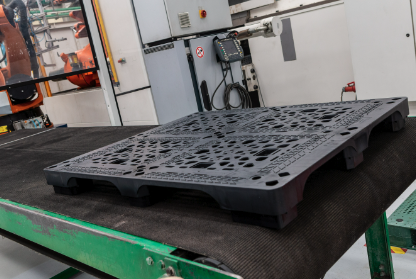 Tarima plástica negra sobre una banda transportadora en una planta industrial